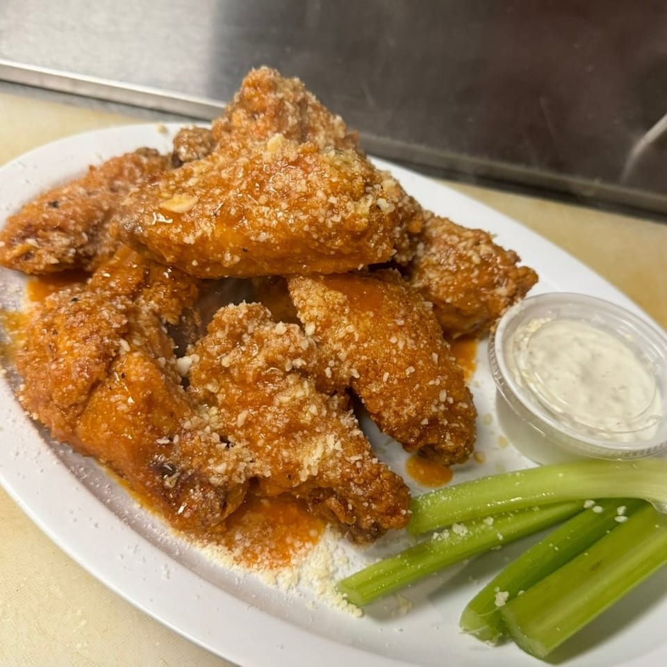 Southwood Bar's buffalo wings, coated in sauce and parmesan, with celery sticks and ranch dressing.