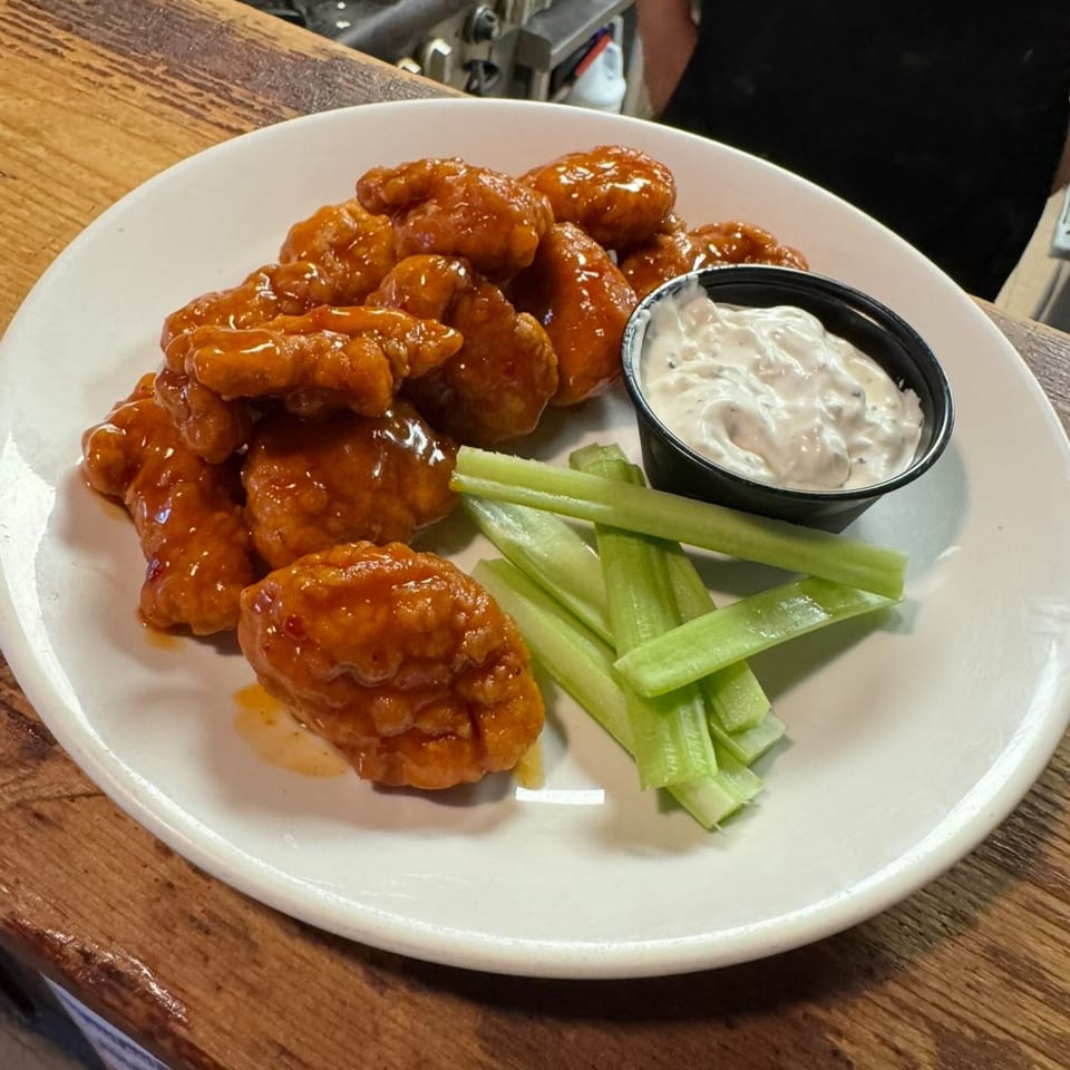 A plate of Southwood Bar's boneless buffalo wings with celery sticks and a side of ranch dressing.