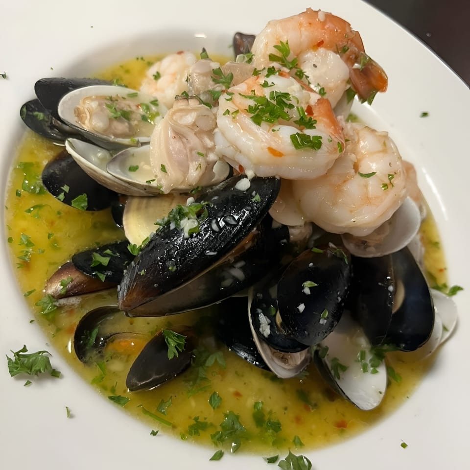 Southwood Bar's seafood dish with mussels, clams, and shrimp in a yellow broth, garnished with parsley.